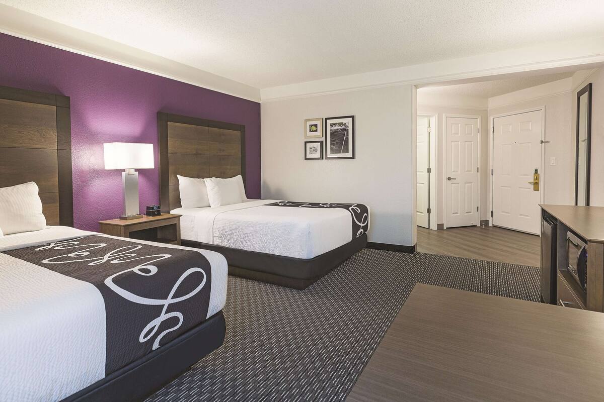 A hotel room with two beds, a desk, and a nightstand.