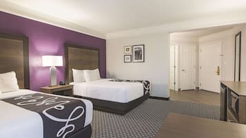 Habitación de hotel con dos camas, un escritorio y una mesita de noche.