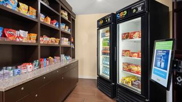 Un mostrador con estantes llenos de papas fritas y diversos bocadillos, y dos vitrinas refrigeradas con bebidas y alimentos.