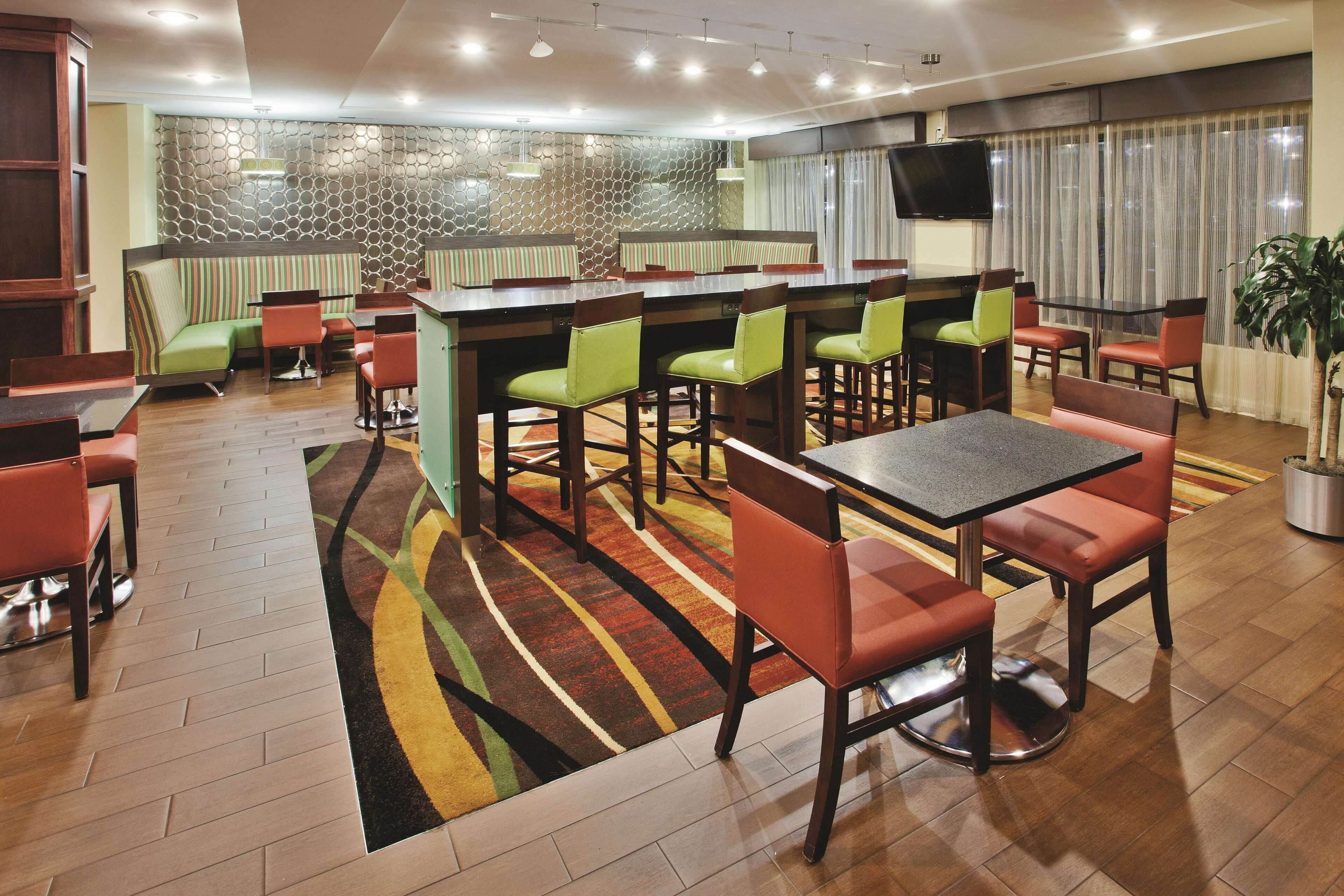 Un restaurant avec des banquettes, des tables hautes et un bar.