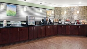 A modern breakfast area with a buffet setup, including a microwave, coffee maker, and various food items. - La Quinta Inn & Suites by Wyndham Florence (Florence)