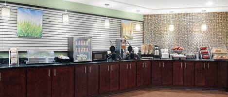 Un espace moderne dédié au petit-déjeuner, avec un buffet proposant un assortiment de produits, ainsi qu’un four à micro-ondes et une machine à café.