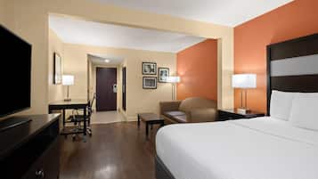A hotel room with a large bed, a desk with a chair, a television, and a small table.