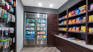 Un espace de libre-service où l’on peut trouver des collations et des boissons, avec des distributeurs de boissons réfrigérés et des étagères remplies de diverses collations et de produits emballés.