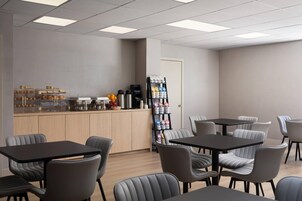 A modern cafe with a wooden counter, seating area, and a coffee machine.