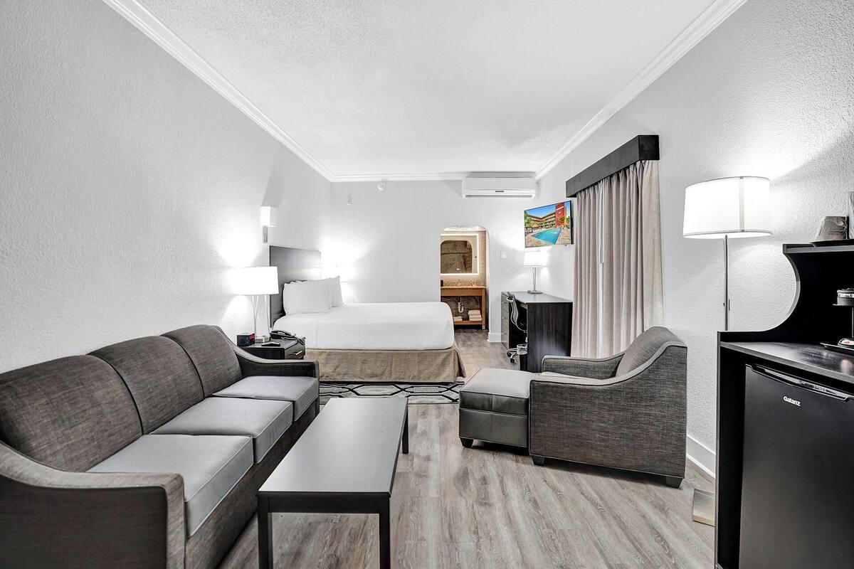 Ein Hotelzimmer mit Bett, Sofa, Schreibtisch, Fernseher und Minibar.
