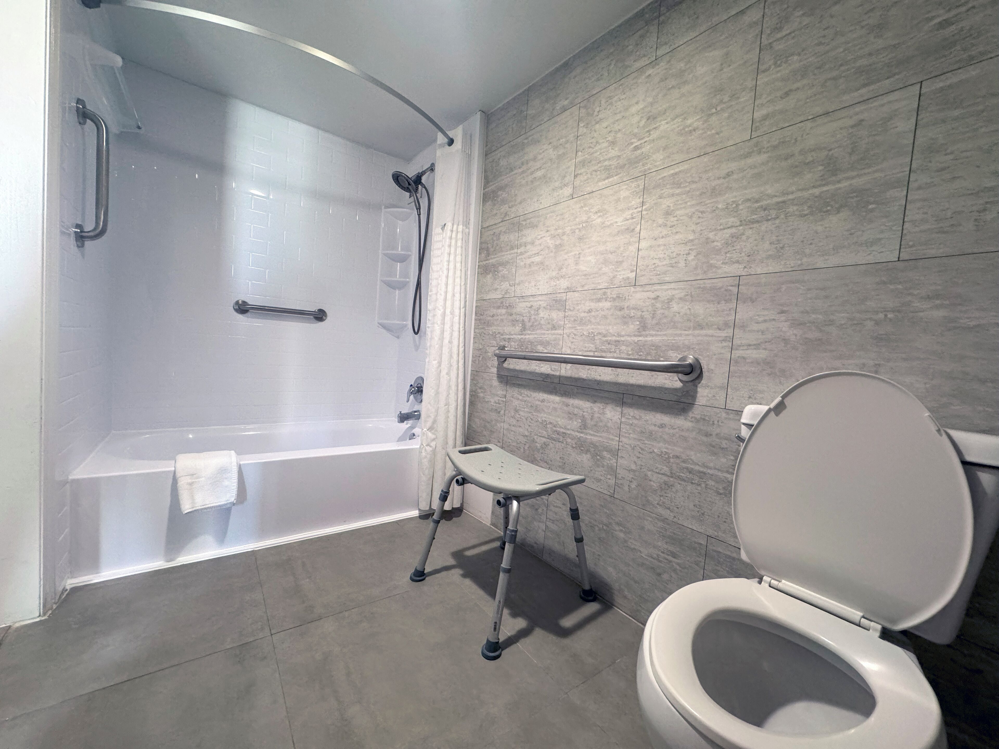 Een moderne badkamer met een badkuip, toilet en een klein opstapkrukje.
