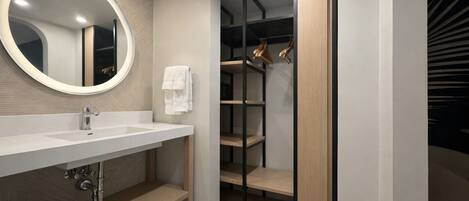 A modern bathroom with a round mirror, white sink, and wooden shelving.