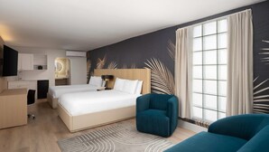 Ein Hotelzimmer mit einem Bett, zwei Stühlen, einem Schreibtisch und einem großen Fenster.