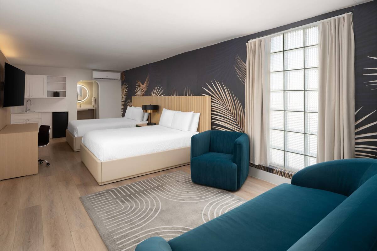 Ein Hotelzimmer mit einem Bett, zwei Stühlen, einem Schreibtisch und einem großen Fenster.