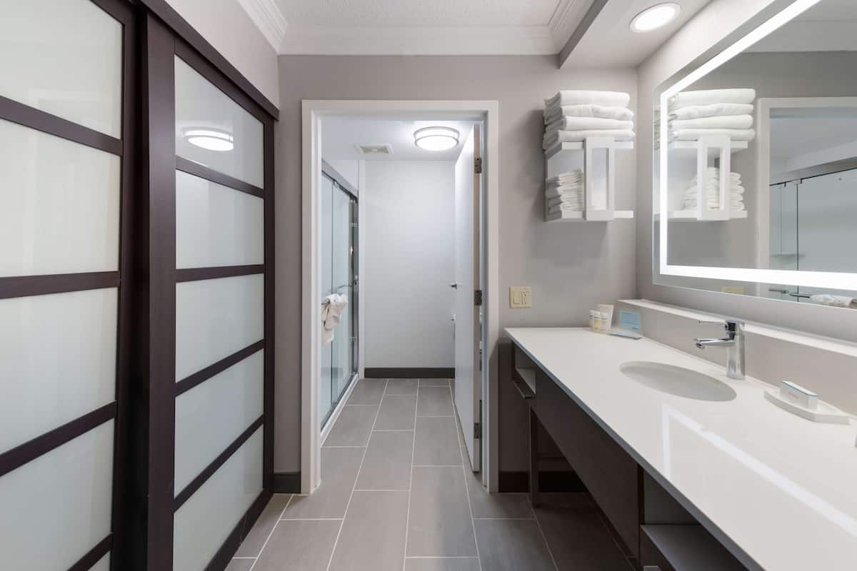 A modern bathroom with a large mirror, white sink, and glass shower enclosure.