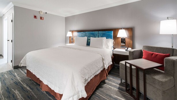 A hotel room with a large bed, a desk, a chair, and a nightstand. - Hampton Inn & Suites Chicago/Hoffman Estates (Hoffman Estates)
