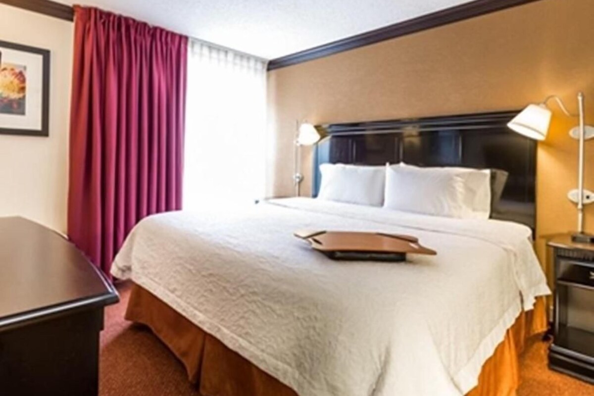 A hotel room with a bed, a desk, and a nightstand.