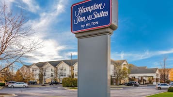 A Hampton Inn & Suites sign with a clear view of the hotel building in the background.