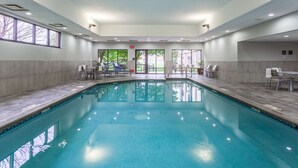 Ein Swimmingpool mit klarem Wasser, umgeben von einer gefliesten Terrasse und Sitzbereichen.