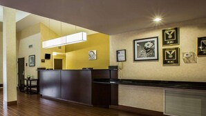 Zona de recepción de un hotel con suelo de madera, mostrador de recepción y premios enmarcados en la pared.
