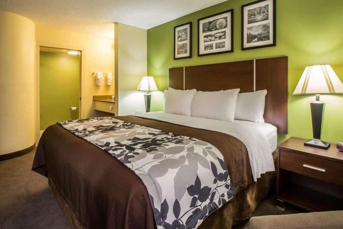 A hotel room with a bed, bedside tables, lamps, and framed pictures on the wall.