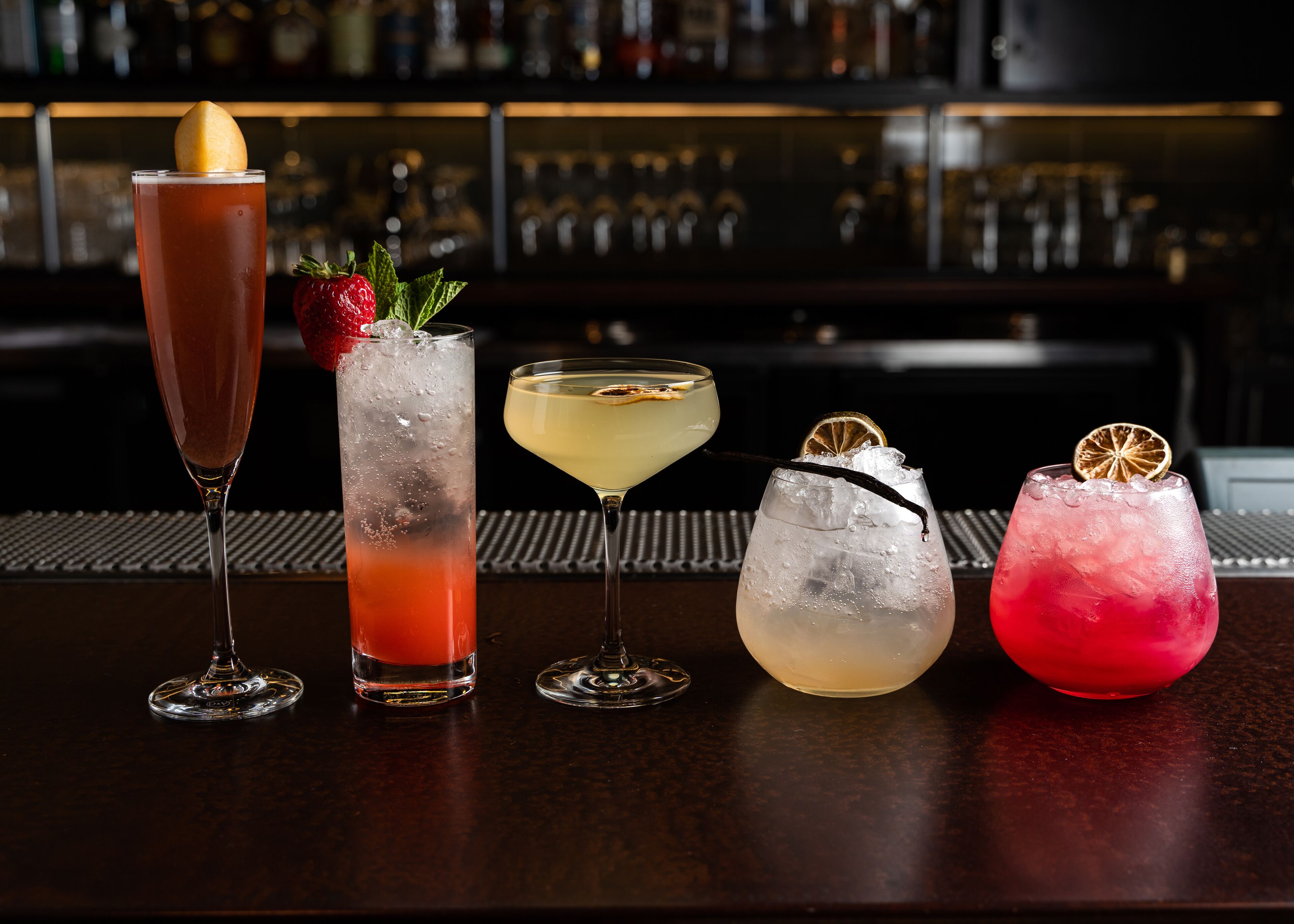 Um bar com quatro cocktails diferentes, cada um com um detalhe decorativo único.