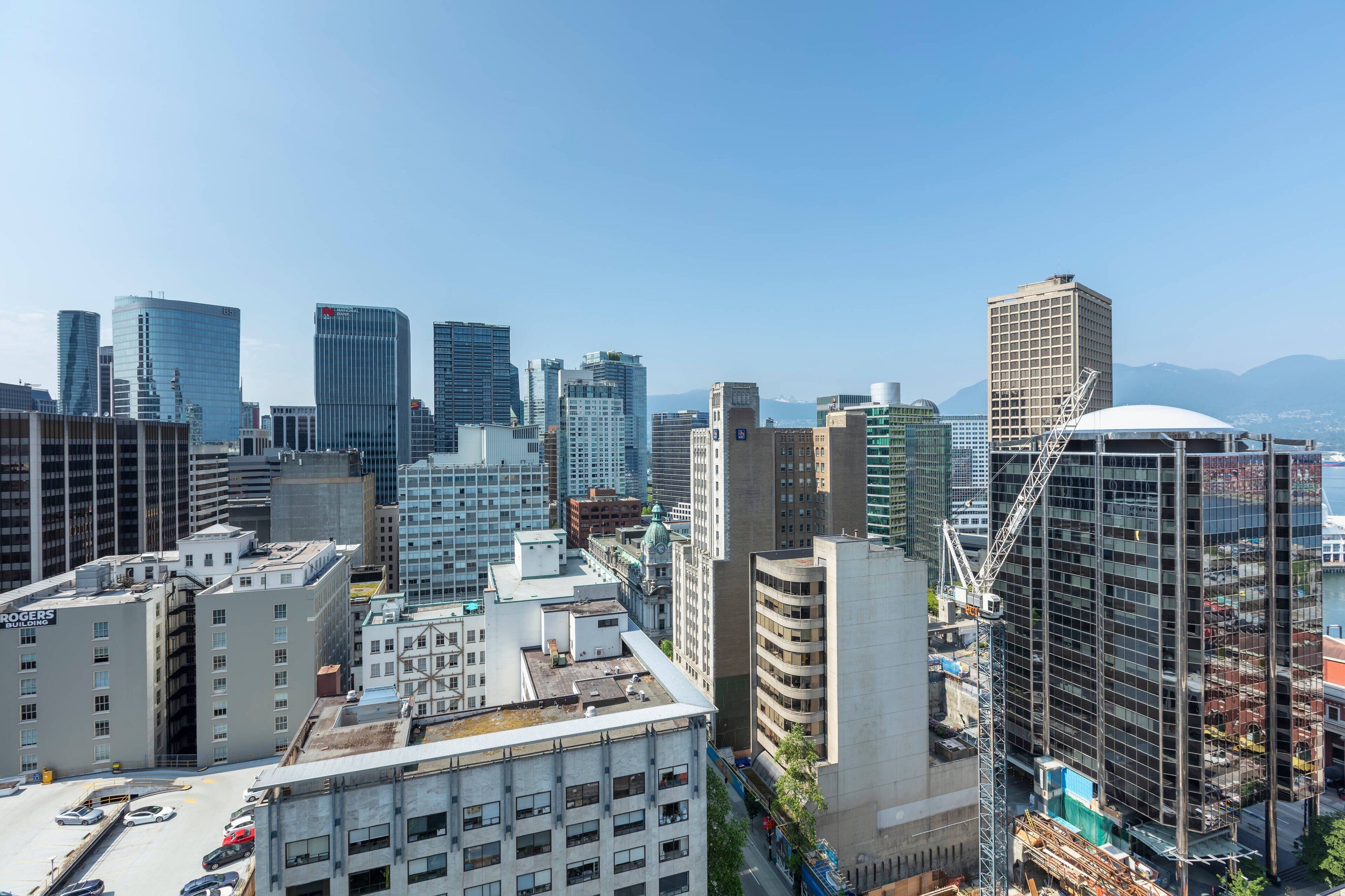A cityscape with modern high-rise buildings, including a construction site with a crane.
