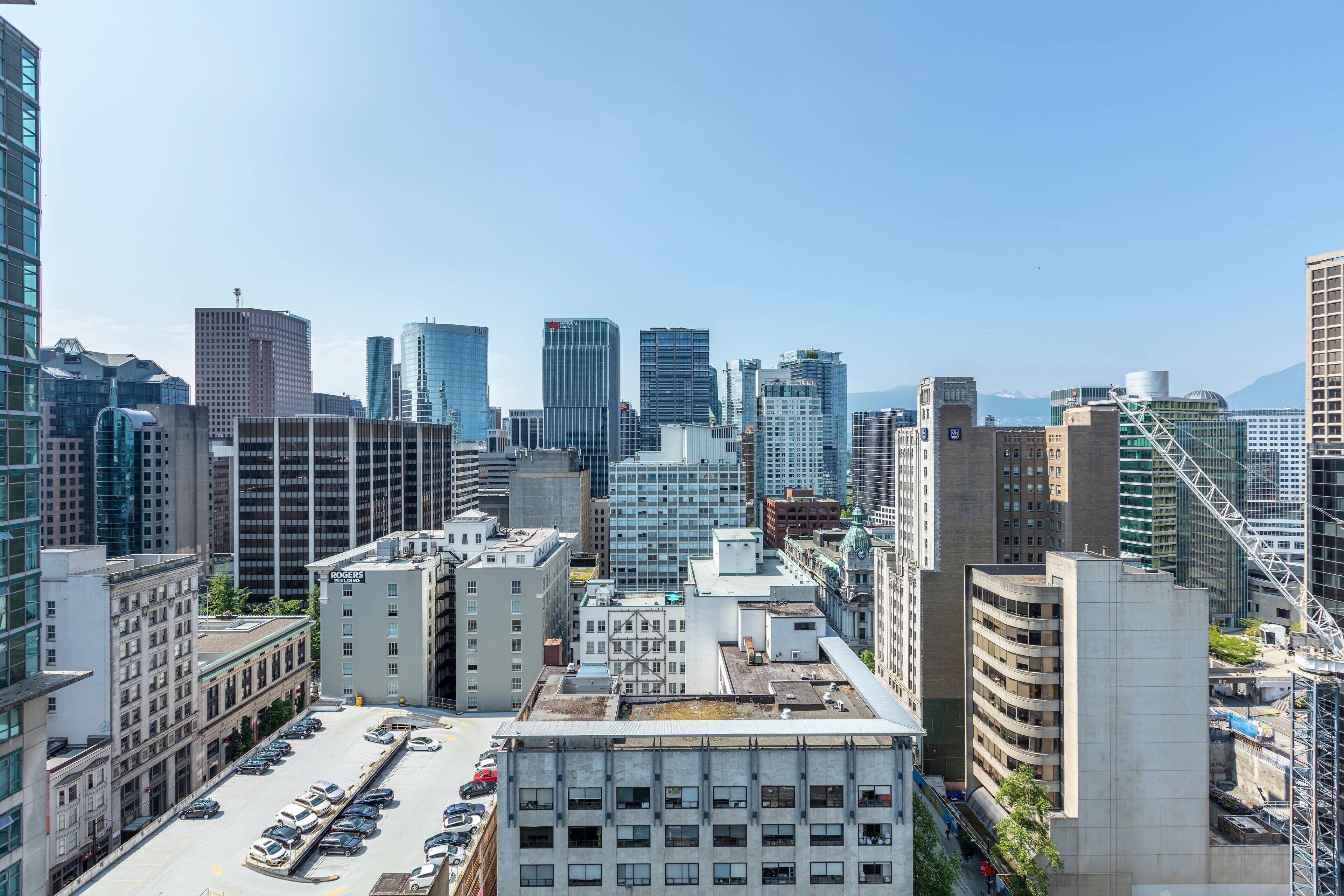 Une vue urbaine avec des immeubles modernes de grande hauteur, un parking et un ciel dégagé.