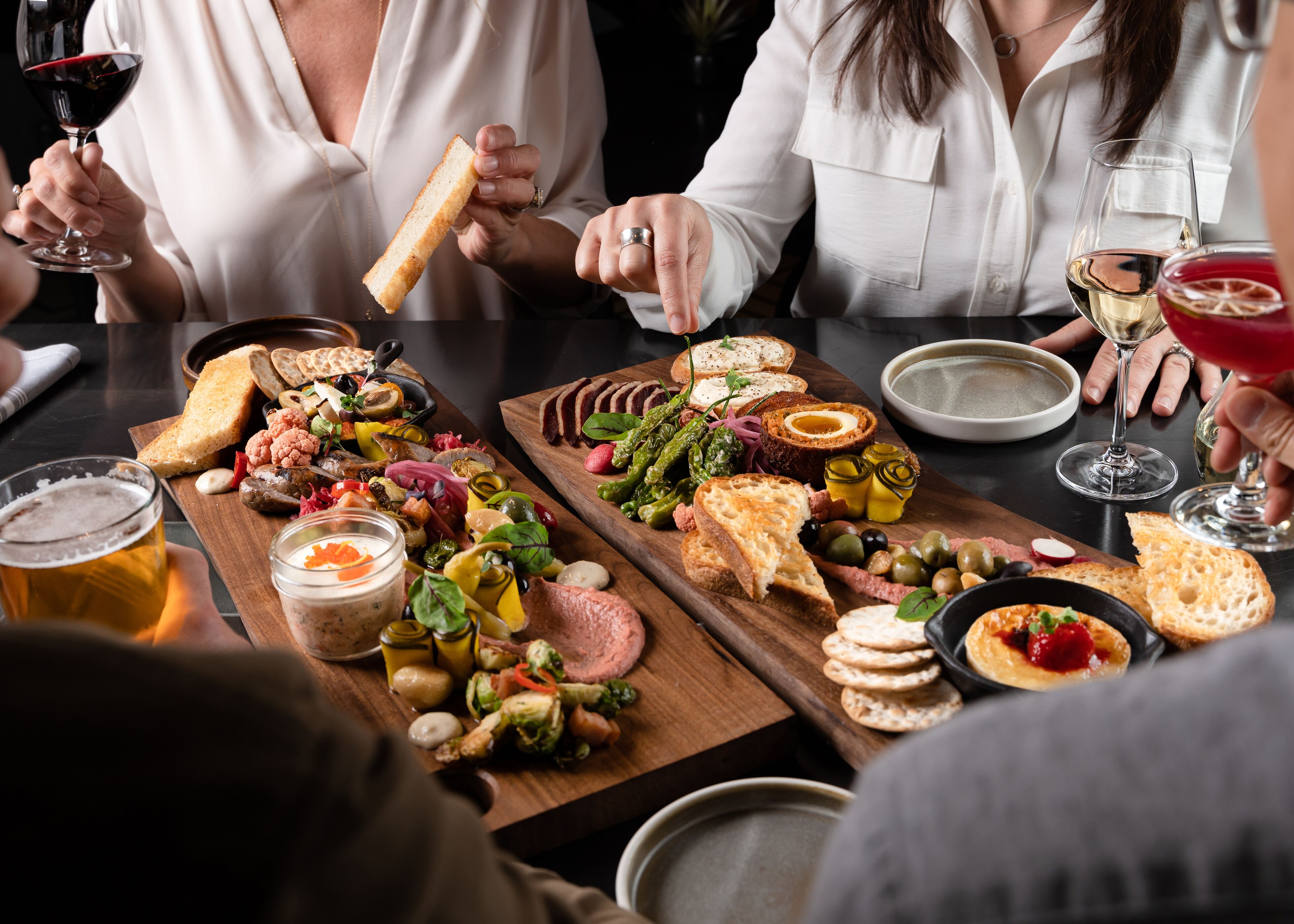 Ein Esstisch mit verschiedenen Speisen und Getränken, darunter Brot, Käse und Oliven.