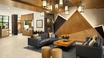 A modern lobby with a reception desk, seating area, and a geometric wall design.
