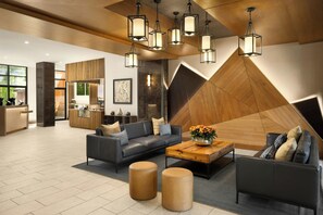 A modern lobby with a reception desk, seating area, and a geometric wall design.
