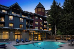 Un hotel con zona de piscina, varios balcones y una torre distintiva.