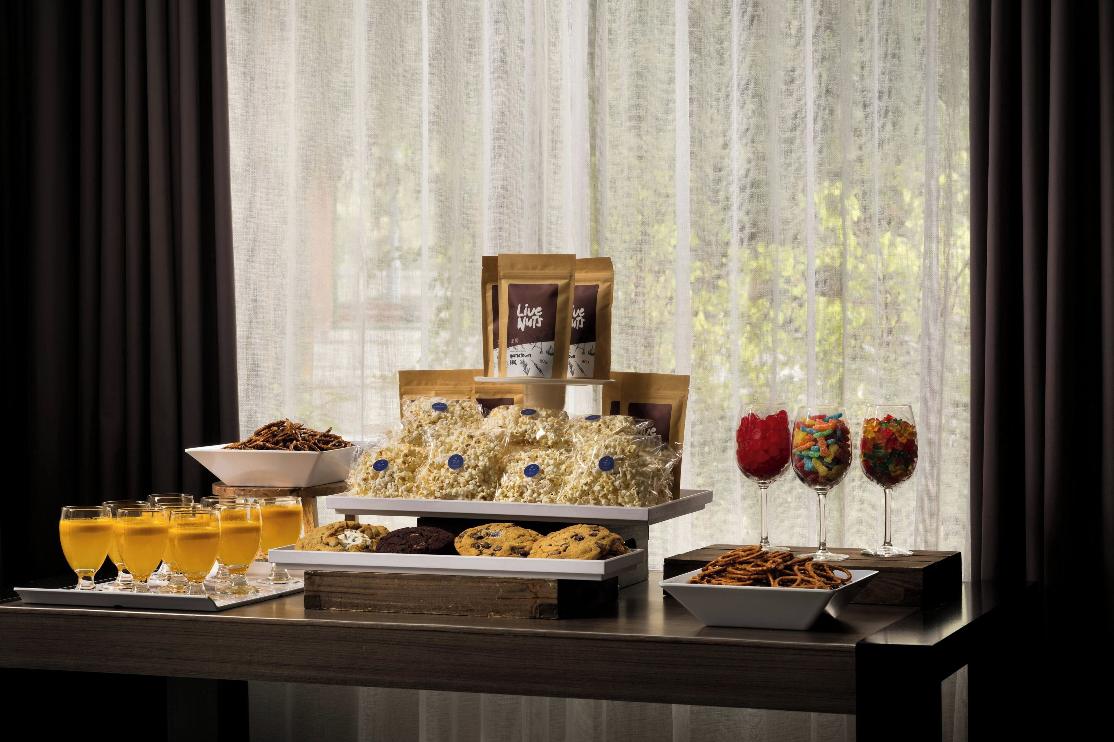 Ein Buffett mit Snacks, Getränken und einem verpackten Produkt mit der Aufschrift 'Live Nuts'.