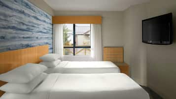 Habitación de hotel con dos camas, televisión, ventana con cortinas y vista al exterior.