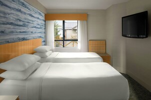 Habitación de hotel con dos camas, televisión, ventana con cortinas y vista al exterior.