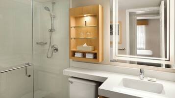 Une salle de bain moderne avec une douche à parois de verre, un meuble-lavabo en bois avec un miroir et des toilettes.