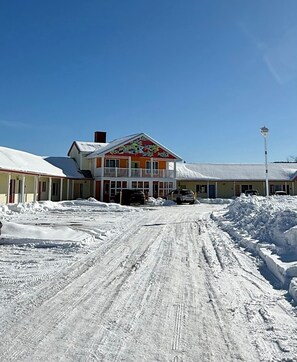 A building with a colorful facade and a snow-covered driveway. - Annapolis Royal Inn & Suites (Annapolis Royal)