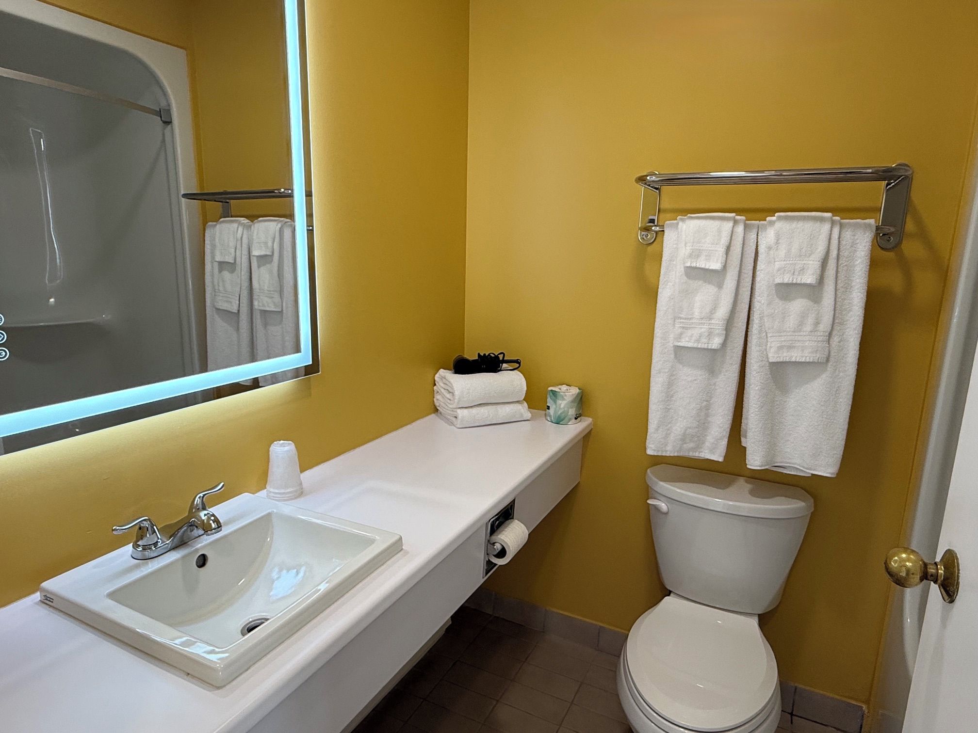 Un baño con un lavamanos blanco, un inodoro y un perchero con toallas.