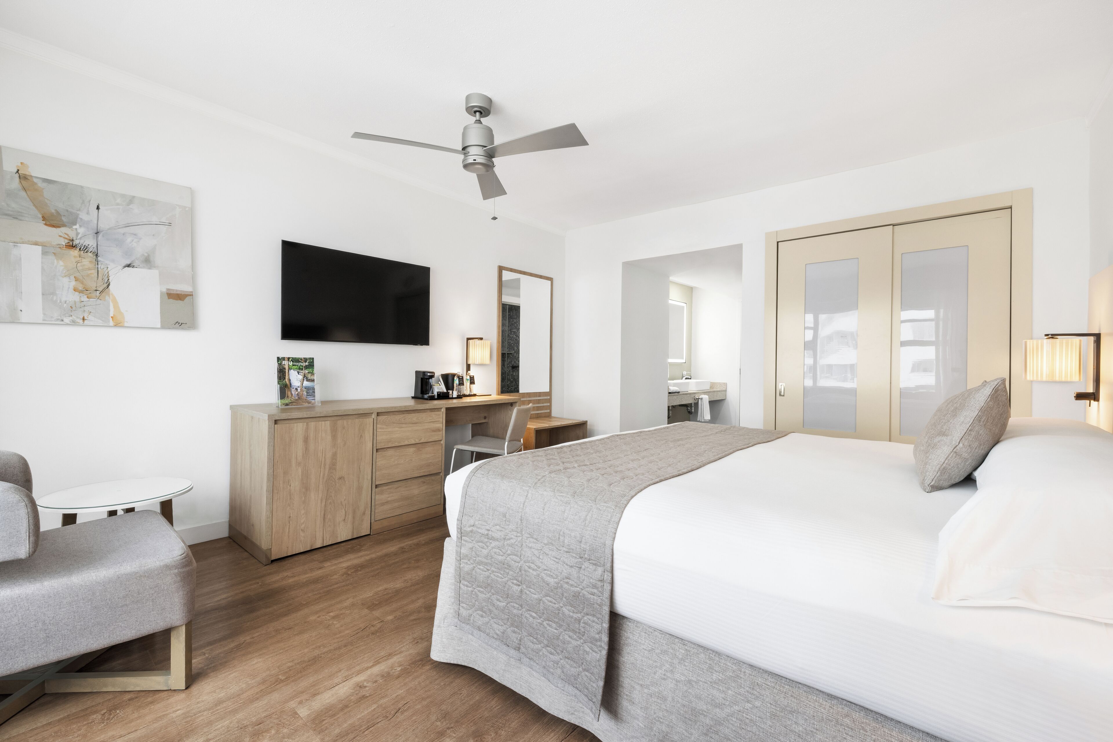 Una camera d'albergo moderna con un letto, una scrivania, una sedia e un televisore.