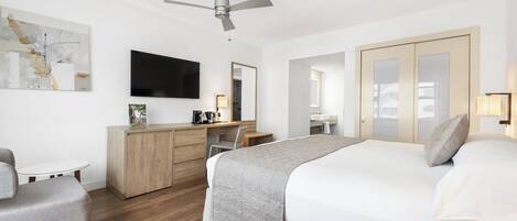 Una habitación de hotel moderna con una cama, escritorio, silla y televisor.