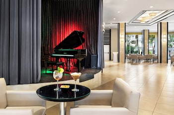 A hotel room with two large white sinks, a ceiling fan, a round mirror, a hairdryer, and a view of the ocean. at Hotel Riu Plaza Miami Beach