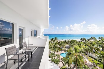 A spacious lobby with a central seating area, large pillars, a modern chandelier, and a reception desk in the background. at Hotel Riu Plaza Miami Beach