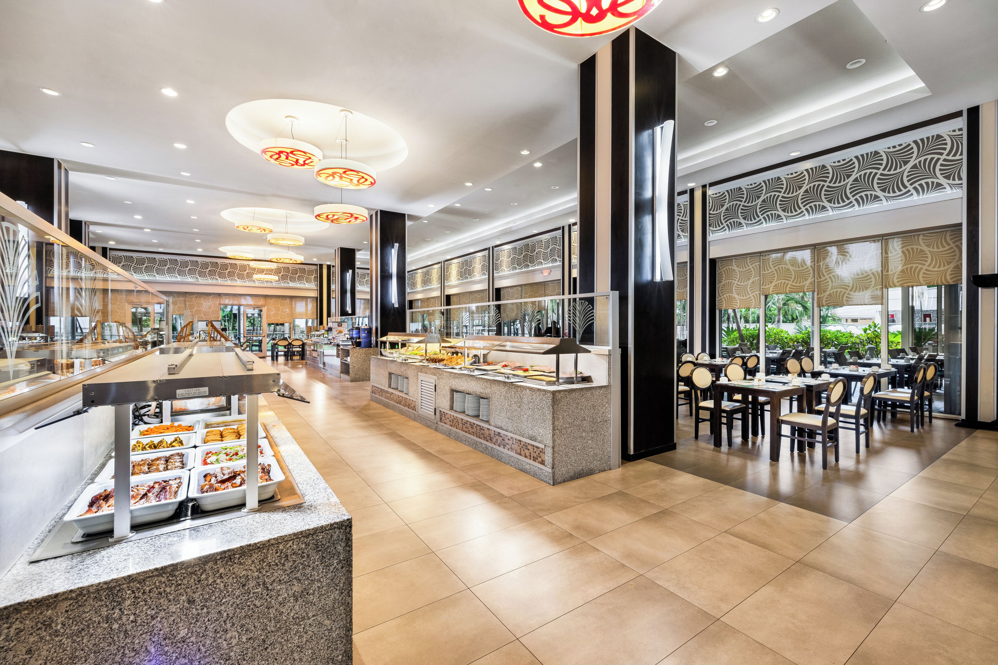 A modern hotel lobby with a buffet area, seating arrangements, and large windows offering views.