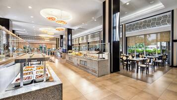 A modern hotel lobby with a buffet area, seating arrangements, and large windows offering views.