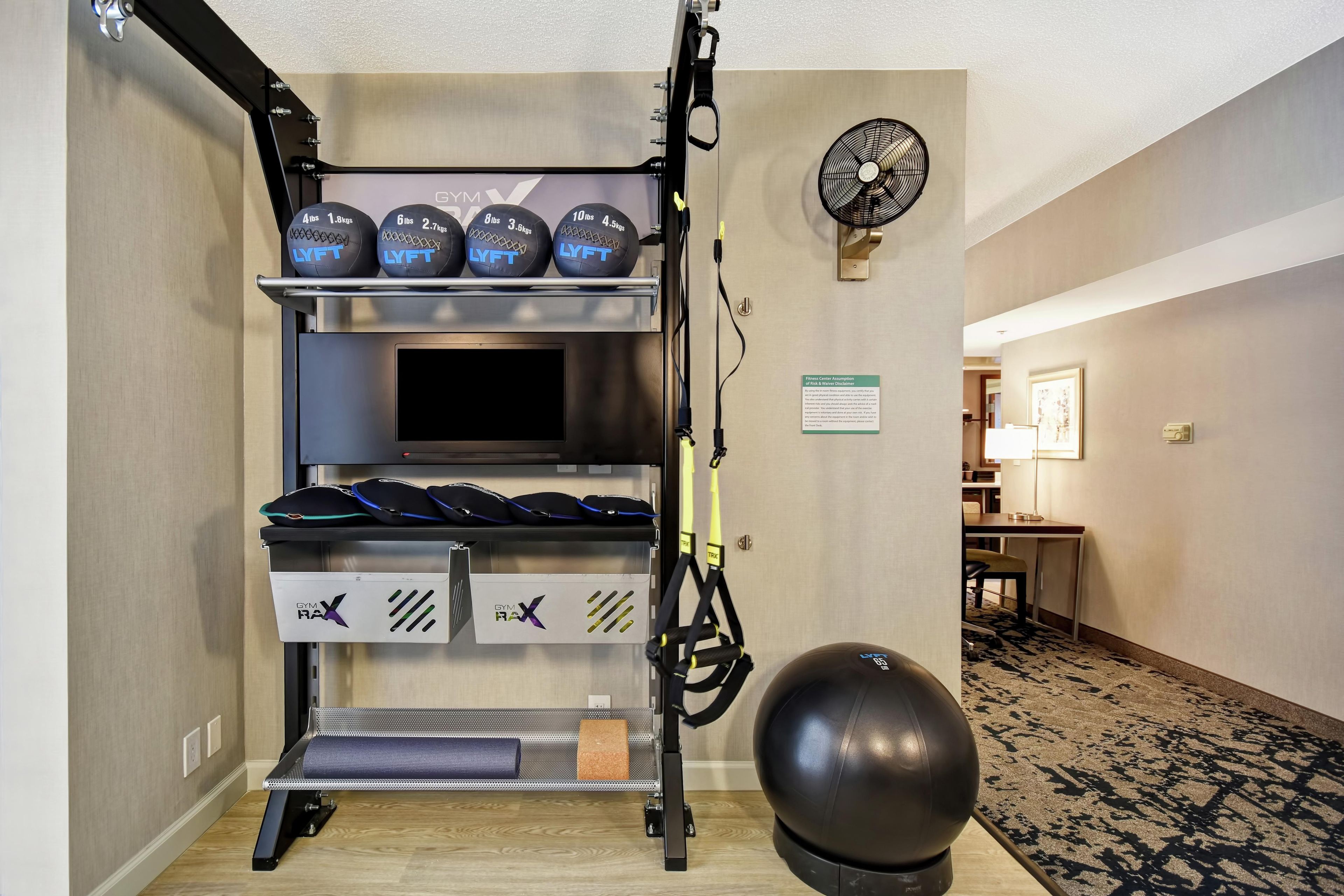 A gym with weightlifting equipment, a TV, and a power ball.