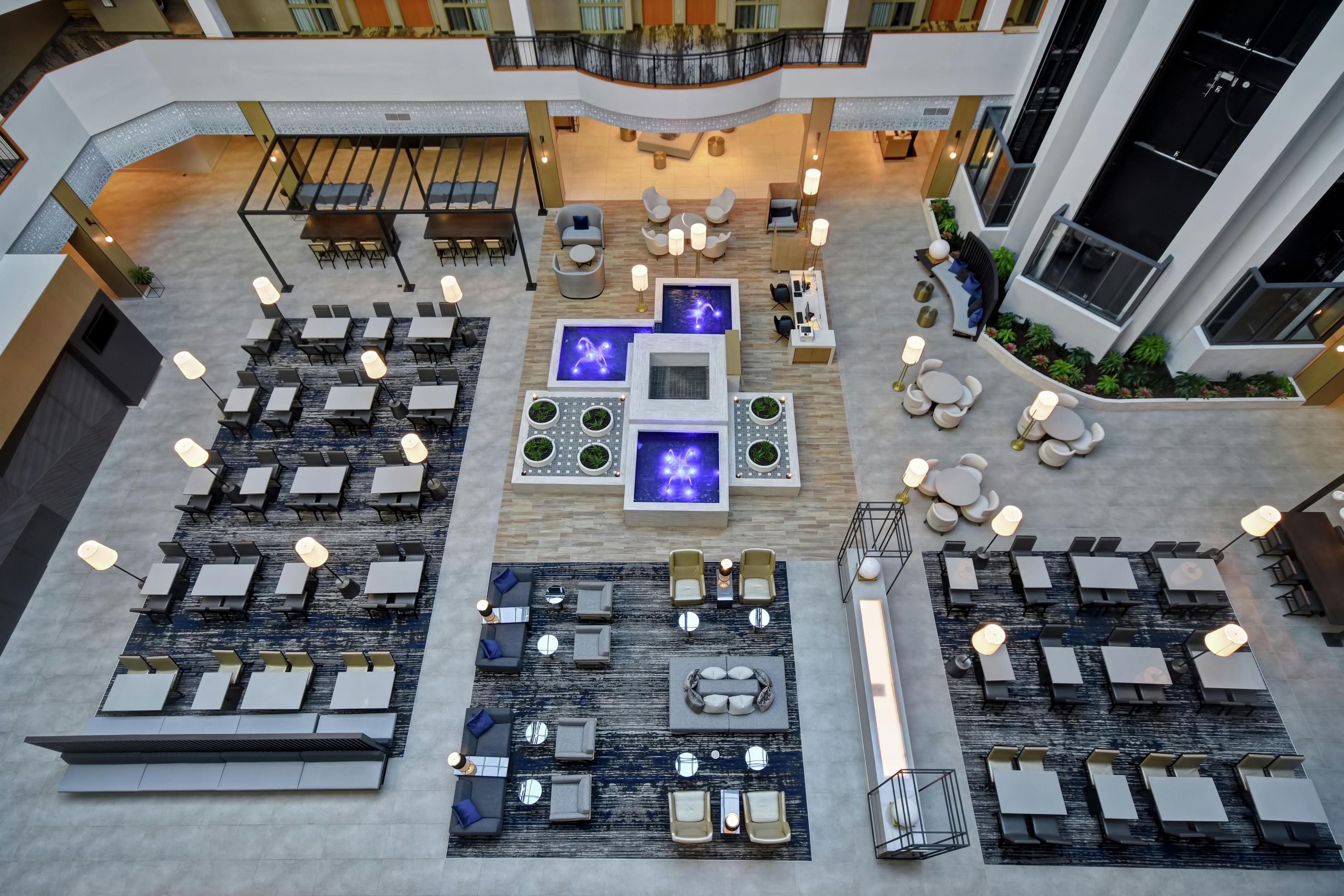 A spacious indoor area with multiple seating arrangements, including tables and chairs, and a central water feature.