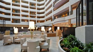Eine mehrstöckige Hotelhalle mit Sitzbereichen, einer Rezeption und einem angelegten Garten.