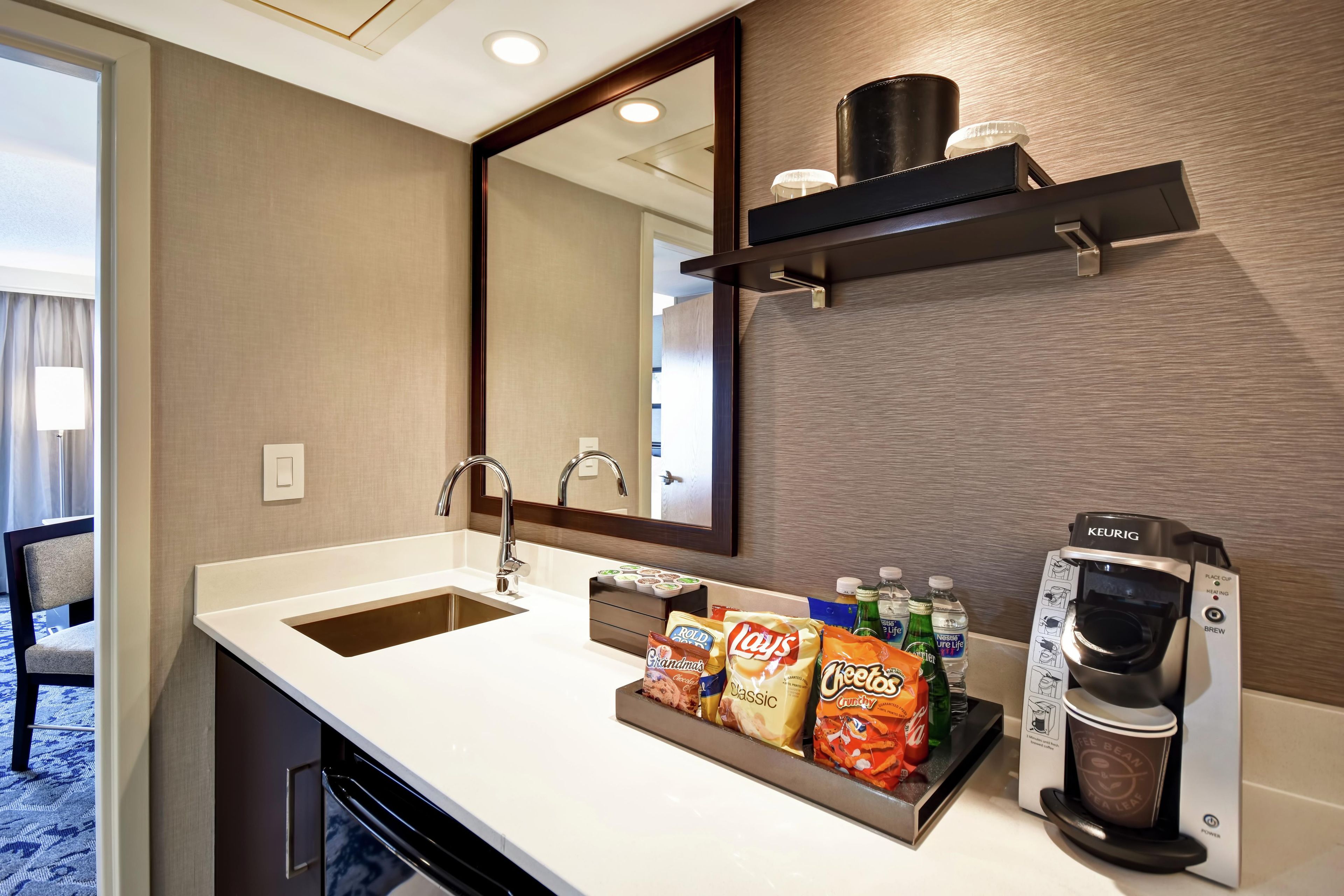 A hotel bathroom with a sink, mirror, and a coffee machine.