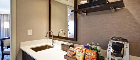 A hotel bathroom with a sink, mirror, and a coffee machine.