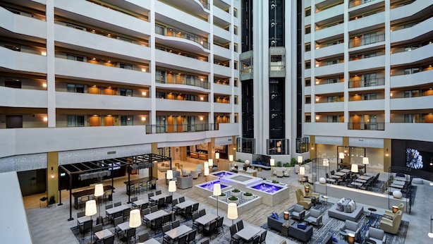 Eine mehrstöckige Hotelhalle mit einem zentralen Atrium, mehreren Speisebereichen und einem Wasserspiel.