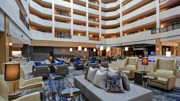 A multi-level hotel lobby with seating areas, a reception desk, and a pool area.