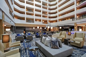 A multi-level hotel lobby with seating areas, a reception desk, and a pool area.