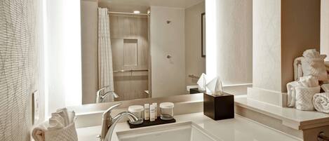 A modern bathroom with a large mirror, a sink, and a shower area.