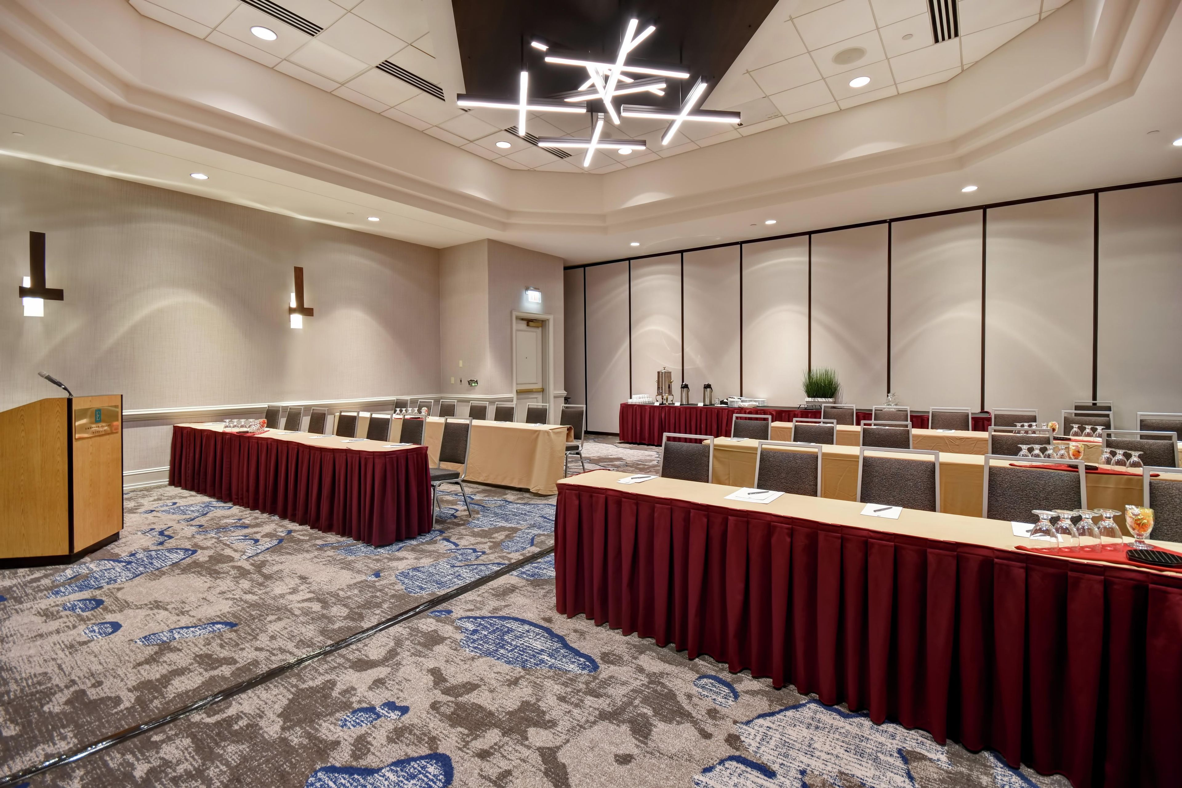A conference room with a long table, multiple chairs, a podium, and a carpeted floor.